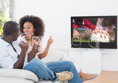 Couple cheering while watching rugby match on television