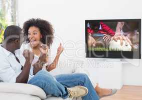 Couple cheering while watching rugby match on television