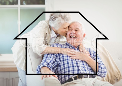 Senior woman giving kiss on senior man cheeks above outline house