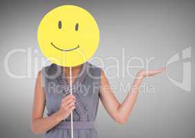 Woman holding a smiley face over her face