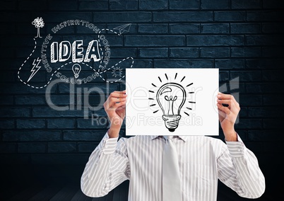 Man holding sheet of paper with drawn light bulb in front of his face and text idea in background
