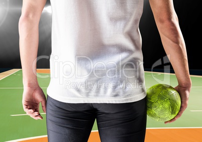 Athlete holding handball against handball picth in background