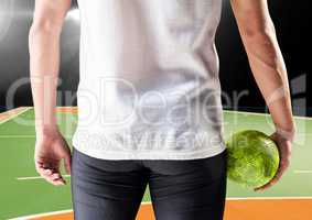 Athlete holding handball against handball picth in background