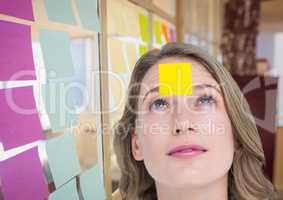 Female executive with sticky note on head in office