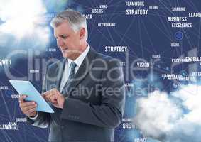 Businessman using digital tablet against business terms in sky