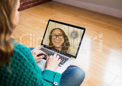 Woman sitting on wooden floor having a video chat with friend on laptop