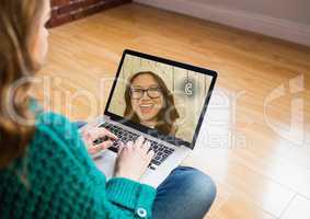 Woman sitting on wooden floor having a video chat with friend on laptop