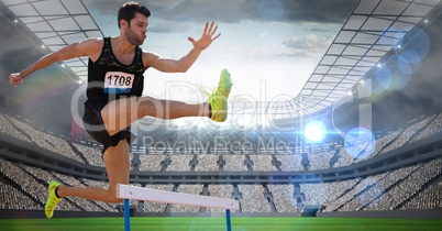 Male athlete jumping above the hurdle in stadium