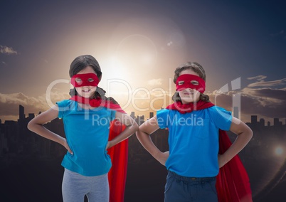 Smiling kids in red cape and mask standing with hand on hip against cityscape