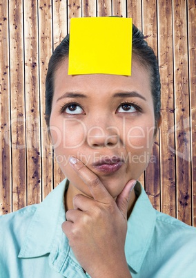 Frustrated woman with sticky note stuck on her forehead against wooden background