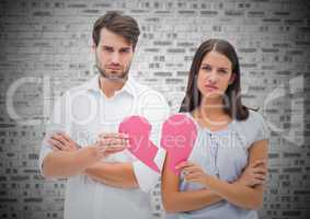Worried couple holding a broken heart