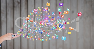 Man using smartphone with various application icons against wooden background