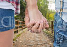 Close-up of couple holding hands against footpath