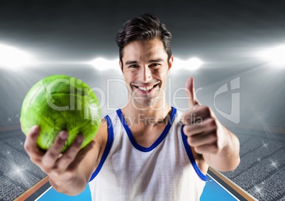Player holding handball and showing thumbs up against stadium in background