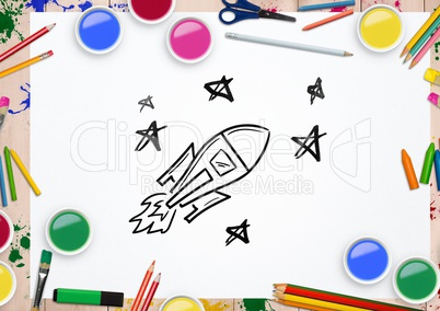 Rocket and stars drawn on paper surrounded with various watercolor and pencils