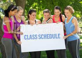 Fit women holding card that reads class schedule