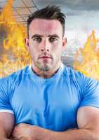 Athlete standing with his arms crossed against fire in background