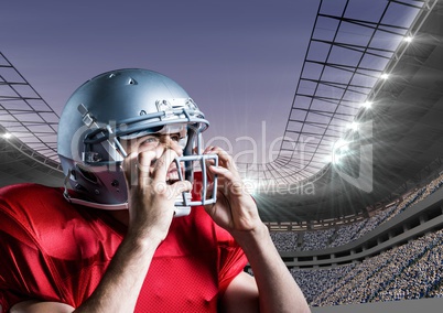 American football player removing his helmet against stadium in background