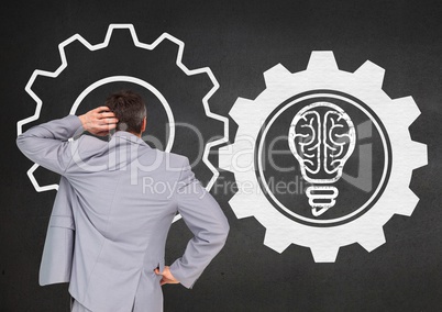 Confused businessman looking at wall with gear wheels and light bulb