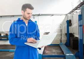 Automobile mechanic using laptop in workshop