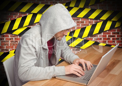 Man working on laptop at desk against caution taped wall in background