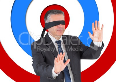 Conceptual image of businessman with black band on eyes against archery board