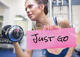Hand holding placard with text just go and woman exercising with dumbbell in background
