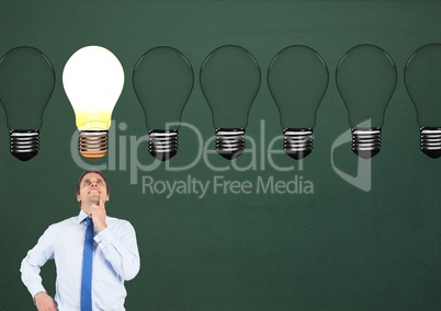 Businessman looking at glowing bulb against green background