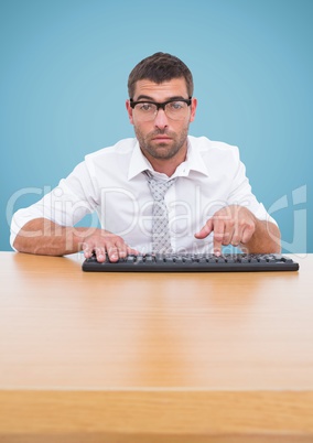 Man in spectacles typing on keyboard against blue background
