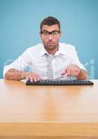Man in spectacles typing on keyboard against blue background