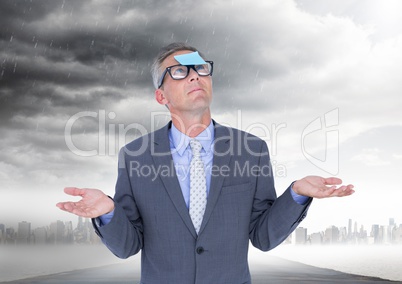 Confused businessman with sticky note stuck on his forehead against stormy sky in background