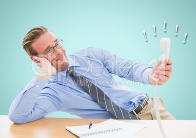 Irritated businessman holding telephone receiver at desk