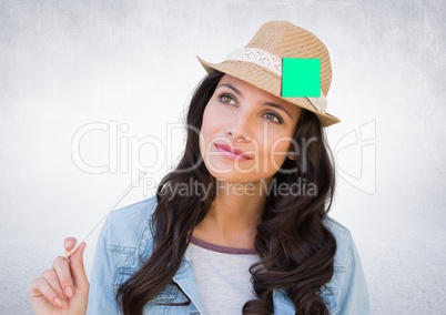 Thoughtful female executive wearing hat with sticky note against white background