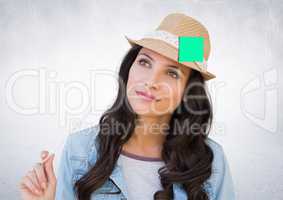 Thoughtful female executive wearing hat with sticky note against white background