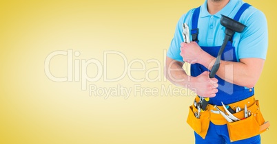 Handy man standing with tools against yellow background