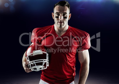 American football player holding a helmet against blue background