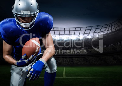 American football player posing with rugby ball in stadium