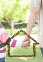 Mother and daughter holding hands against house outline in background