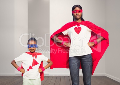 Mother and daughter in superhero costume standing with hands on hips