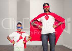 Mother and daughter in superhero costume standing with hands on hips