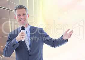 Businessman public speaking on microphone against bright sunlight