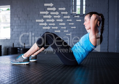 Fit woman performing crunches exercise in gym against direction arrows in background