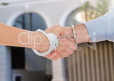 Handcuffed business people shaking hands