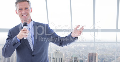 Businessman speaking with microphone against cityscape in background