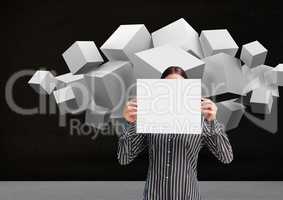 Woman holding blank sheet of paper in front of her face and white cubes in background