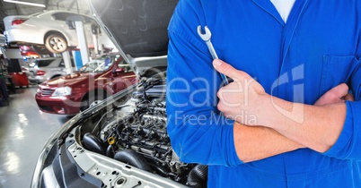 Mid section of automobile mechanic holding a wrench in workshop