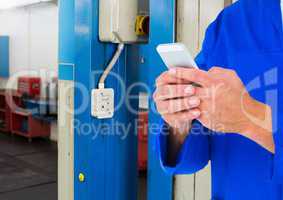 Automobile mechanic using mobile phone in workshop