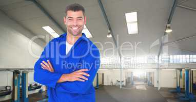 Happy automobile mechanic standing with arms crossed in workshop