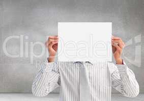 Male executive covering his face behind paper against grey background