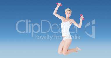 Fit woman with dumbbells jumping against blue background